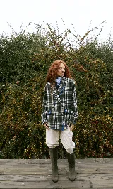 Blazer sastrero de corte oversize, con diseño a cuadros en tonos verdes y blancos. Presenta cuello solapa, cierre frontal con botones, dos bolsillos laterales de vivo y detalles bordados con hilo en contraste en los bordes. El interior está forrado en satén.