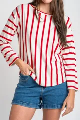 Remeron de corte oversize con cuello redondo y mangas largas. Presenta un diseño de rayas verticales en color rojo sobre base color crema.