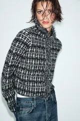 Chaqueta de punto con textura, cuello redondo y manga larga. Presenta detalles de acabados deshilachados en los bordes y cierre frontal con ganchos.