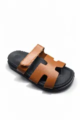 Sandalias planas con base negra y capellada de cuero sintético color suela con diseño de letra H recortada y ajuste con velcro.