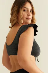 Top de bikini negro con efecto lurex, volados en los hombros y nudo regulable en el escote.