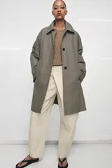 Trench oversize de Zara Woman Collection, confeccionado en hilatura de algodón. Presenta cuello solapa, manga larga, bolsillos delanteros y cierre frontal con botones ocultos bajo solapa.