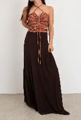 Vestido largo estilo halter con parte superior de tejido estampado multicolor a rayas y falda larga fluida de color marrón oscuro. Presenta tirantes cruzados al cuello y cordones decorativos frontales.