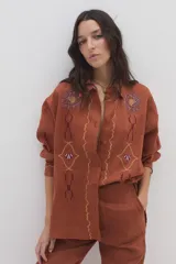 Camisa de lino color ladrillo, con mangas largas y bordados decorativos en el pecho y las mangas.