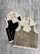 Chaleco estilo gamulán de gamuza color marrón con interior y bordes de corderito sintético color crema. Presenta cierre frontal metálico, bolsillos laterales con cierre y detalles de tiras de cuero sintético en la cintura.
