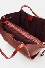 Bolso tipo shopper color rojo de hombro, con detalle de lazos en los laterales y doble asa.
