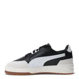 Championes Puma modelo Shuffle Downtown, de diseño retro urbano. Presentan una base blanca con detalles en negro, incluyendo la franja lateral característica de la marca, y refuerzos de gamuza en la puntera y el talón. Cuentan con suela de goma color caramelo y plantilla SoftFoam+ para mayor confort.