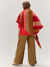 Chal envolvente con diseño de rayas horizontales en tonos beige, tostado y rosado claro, confeccionado en tejido de punto.