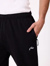 Babucha gris de algodón y poliéster, con cintura elástica, cordón ajustable y bolsillos laterales. Presenta el logo de Rusty bordado en el muslo izquierdo.