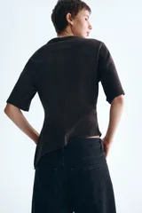 Remera marrón de punto suave de algodón, con cuello redondo, mangas cortas amplias y diseño asimétrico con frunce lateral.