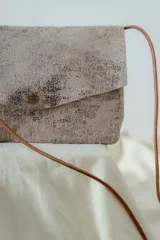 Cartera tipo pouch plateada con textura metalizada y correa fina al hombro.