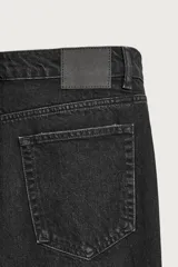 Jeans de corte recto y tiro medio, confeccionados en denim de algodón color negro con efecto deslavado y acabado rígido. Cuenta con diseño clásico de cinco bolsillos y cierre frontal con botones.