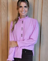 Camisa de manga larga con estampado a cuadros en tonos verde oscuro y beige. Presenta cuello alto con volados, cierre frontal con botones y puños con volados elásticos.