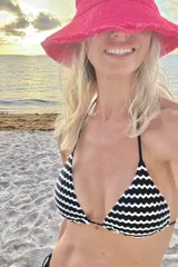 Top de bikini tipo triángulo de tirantes finos negros, con patrón de ondas blancas y negras en relieve. Presenta un pequeño dije en forma de corazón en el centro.