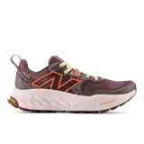 Championes de trail running New Balance modelo Hierro v8, color bordó con detalles en naranja y suela clara. Presentan tecnología de amortiguación Fresh Foam X en la mediasuela y suela Vibram Eco-Step Natural para mayor tracción y durabilidad en terrenos irregulares.