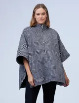 Poncho de tejido soft con estampado de cuadros, cuello alto y cierre frontal parcial. Presenta diseño holgado con mangas amplias y bolsillos laterales.