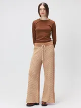 Pantalón de tejido jacquard con textura geométrica en tonos tostado y beige, de tiro medio, cintura elástica con cordón de ajuste y pierna ancha.