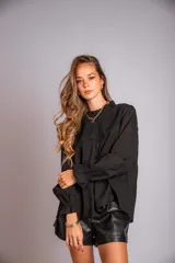 Camisa negra de mangas largas con cuello alto con volados y detalles de crochet en el frente.