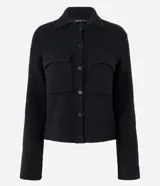 Campera de punto con textura, corte recto y cuello clásico. Presenta cierre frontal con botones y dos bolsillos aplicados con solapa en el pecho.