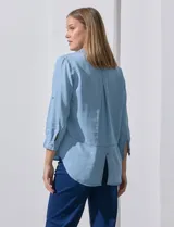 Camisa gris de tencel con cuello con solapa, escote en V y abertura central con botones. Largo de manga regulable con presilla y botón. Ruedo en espalda con tajo.