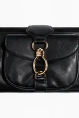 Cartera de hombro de diseño rectangular alargado, confeccionada en tejido revestido de color negro con herrajes metálicos dorados. Cuenta con un compartimento exterior con solapa y cierre de argolla metálica, cierre superior con cremallera y asa ajustable.