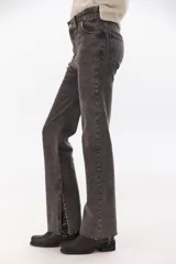 Pantalón de jean gris oscuro, de corte recto, tiro alto y tajos laterales en el ruedo.