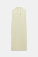 Vestido midi de Zara Woman Collection confeccionado en hilatura de viscosa con tejido satinado, de color beige. Presenta cuello subido, diseño sin mangas (manga sisa), bajo recto con aberturas laterales y cierre en la espalda con alamares.