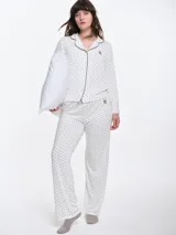 Camisa de pijama de manga larga con cuello solapa y cierre frontal de botones. Presenta un estampado sutil de pequeños corazones sobre una base de color gris melange, con detalles de ribete en contraste en el cuello y la botonera.