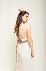 Vestido midi color crema de lino con breteles finos y escote en V. Incluye cinturón trenzado de cuero con argollas de bronce.