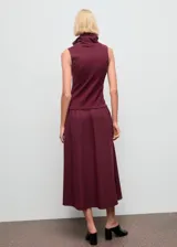 Vestido midi de diseño combinado en color bordó. Presenta un cuerpo sin mangas con cuello embudo y una falda de corte recto con caída fluida.