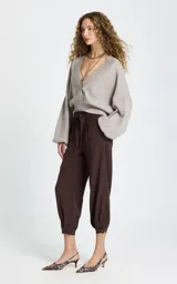 Pantalon de corte holgado color marrón, con cintura elástica ajustable mediante cordón, bolsillos laterales y puños abotonados en el bajo.