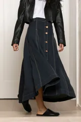 Falda larga de jean azul oscuro con pespuntes en color ocre y botones frontales. De corte acampanado y buena caída.