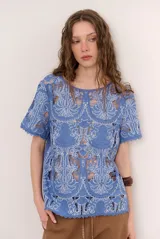 Blusa de encaje con diseño floral y geométrico translúcido, de manga corta y cuello redondo.
