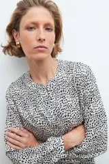 Blusa beige con estampado de lunares negros, cuello en V y mangas largas.