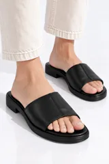 Sandalias planas de eco cuero color negro, con tira ancha superior y suela cómoda.