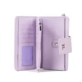 Billetera tipo clutch color lila con solapa frontal y cierre de botón a presión. Presenta un dije metálico con las letras "XL" en el centro. Incluye una correa de muñeca desmontable.