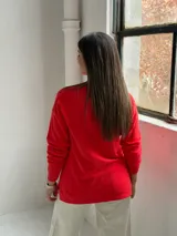 Sweater de punto color rojo con diseño de rombos en relieve, cuello redondo y mangas largas con puños acanalados.