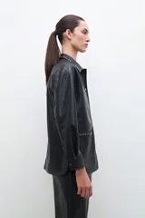 Sobrecamisa negra de cuero sintético con cuello camisero y tachas plateadas.
