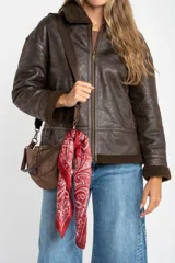 Campera tipo gamulán de corte oversize, color marrón oscuro con efecto cuero envejecido. Presenta cuello solapa, puños y ruedo con forro de corderito sintético en tono marrón oscuro. Cuenta con cierre frontal completo y detalles de costuras reforzadas.