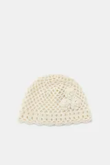 Gorro tipo casquete de crochet color crema, con tejido de red y tres flores aplicadas en relieve en un lateral.