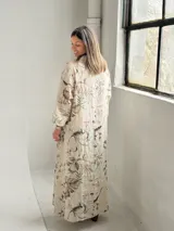 Vestido largo beige con diseño estampado de flores, cuello redondo amplio y mangas largas holgadas.