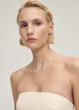 Top de corte peplum con diseño palabra de honor, sin mangas y cierre de cremallera en la parte posterior.