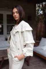 Campera de jean blanca con volados en el frente y las mangas, confeccionada en algodón y lino.