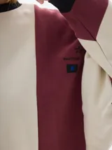 Buzo de friza con cortes verticales en color bordó y beige, calce oversized, manga larga, hombros caídos y cuello a la base.