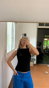 Top sin mangas de color negro, confeccionado en tela elastizada con textura acanalada y ajuste al cuerpo.