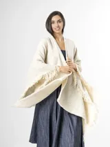 Ruana off white de tejido texturado con detalles sutiles de hilos multicolor y terminación de flecos en los bordes.