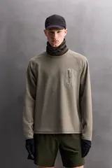 Camiseta relaxed fit de color verde militar, confeccionada en tejido con estructura waffle. Tiene cuello redondo, manga larga con puño elástico y un bolsillo plastrón con cierre de cremallera en el pecho.