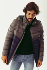 Campera puffer de abrigo con diseño bicolor, gris en la parte superior y violeta oscuro en la inferior. Cuenta con cierre frontal completo, capucha desmontable, bolsillos laterales con cierre y logo estampado en el pecho.