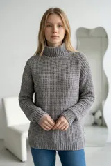 Sweater de cuello alto tipo polera, confeccionado en tejido de chenille con textura de relieve tipo waffle. Presenta mangas largas con puños acanalados y ruedo también acanalado.