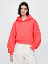 Buzo tipo canguro de la marca Gap, color coral, con capucha y logo de la marca bordado en el mismo tono en el frente. Presenta un corte holgado y diseño cropped con puños y ruedo acanalados.